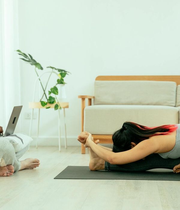 Man performing a stretching exercise on a yoga mat in a bright room.